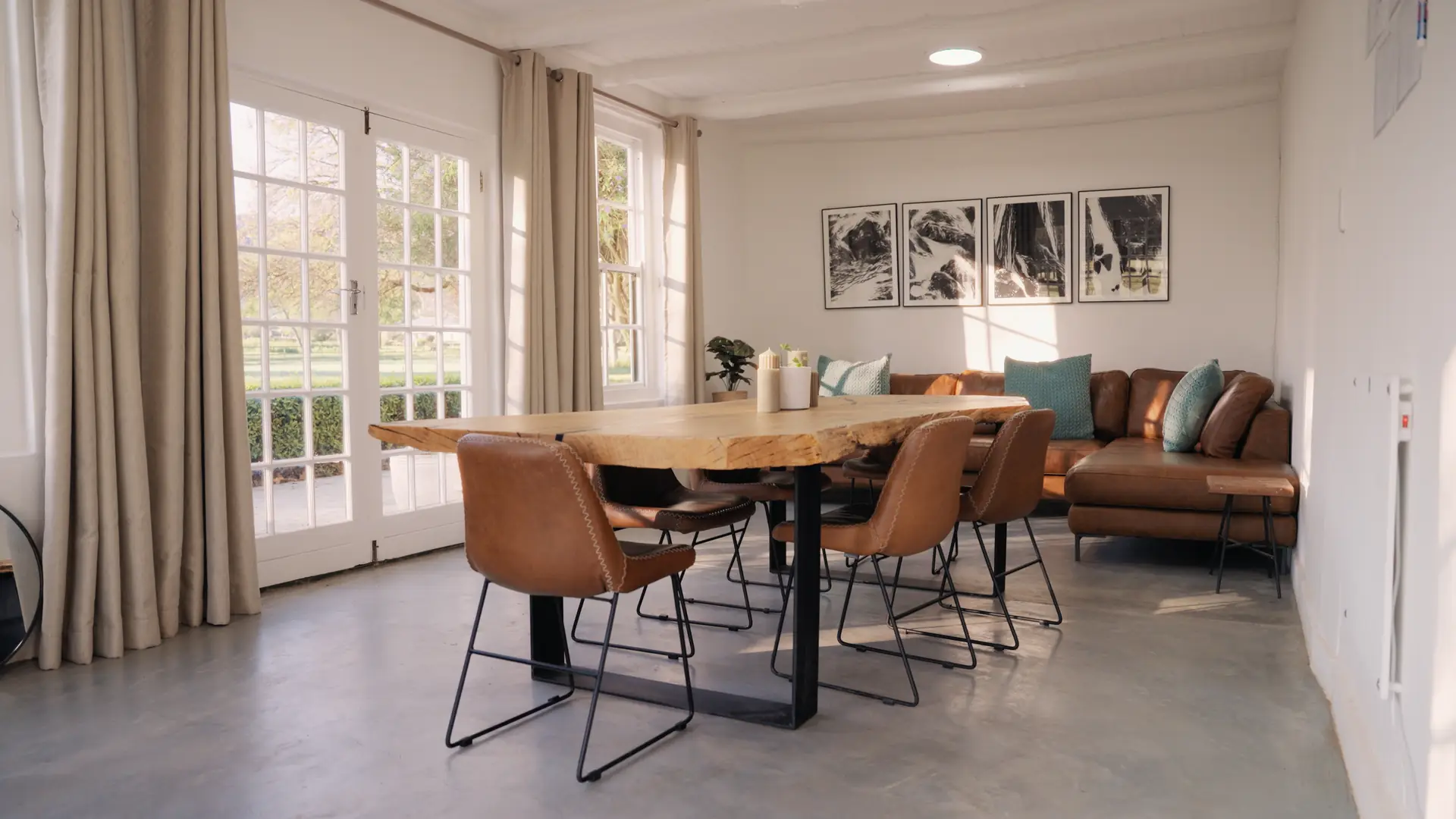The meeting room in the cottage at Banhoek Stud: a live-edge oak table, leather chairs and a corner sofa under equestrian prints