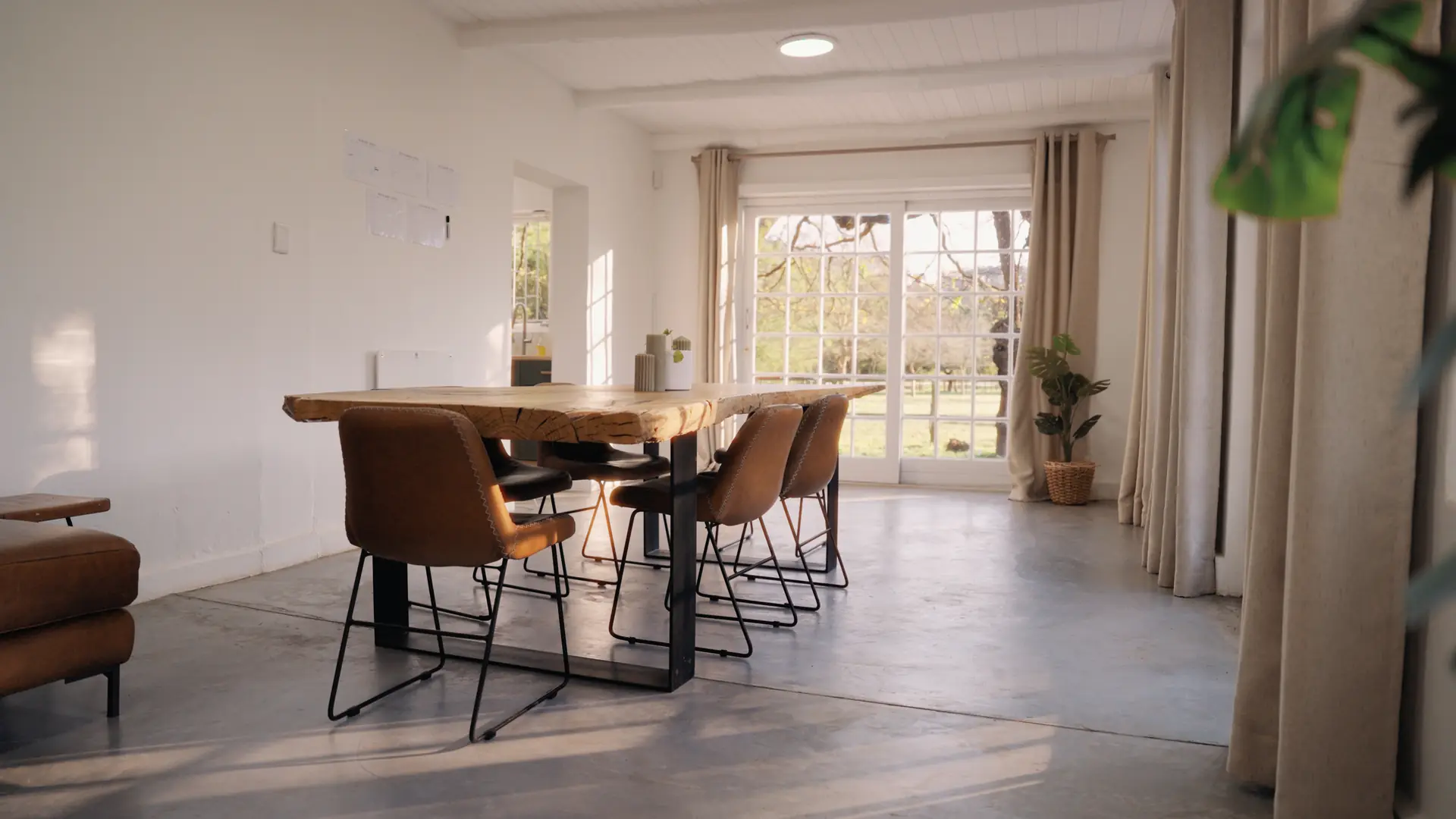 The long oak table in the cottage at Banhoek Stud, garden light through the glass doors