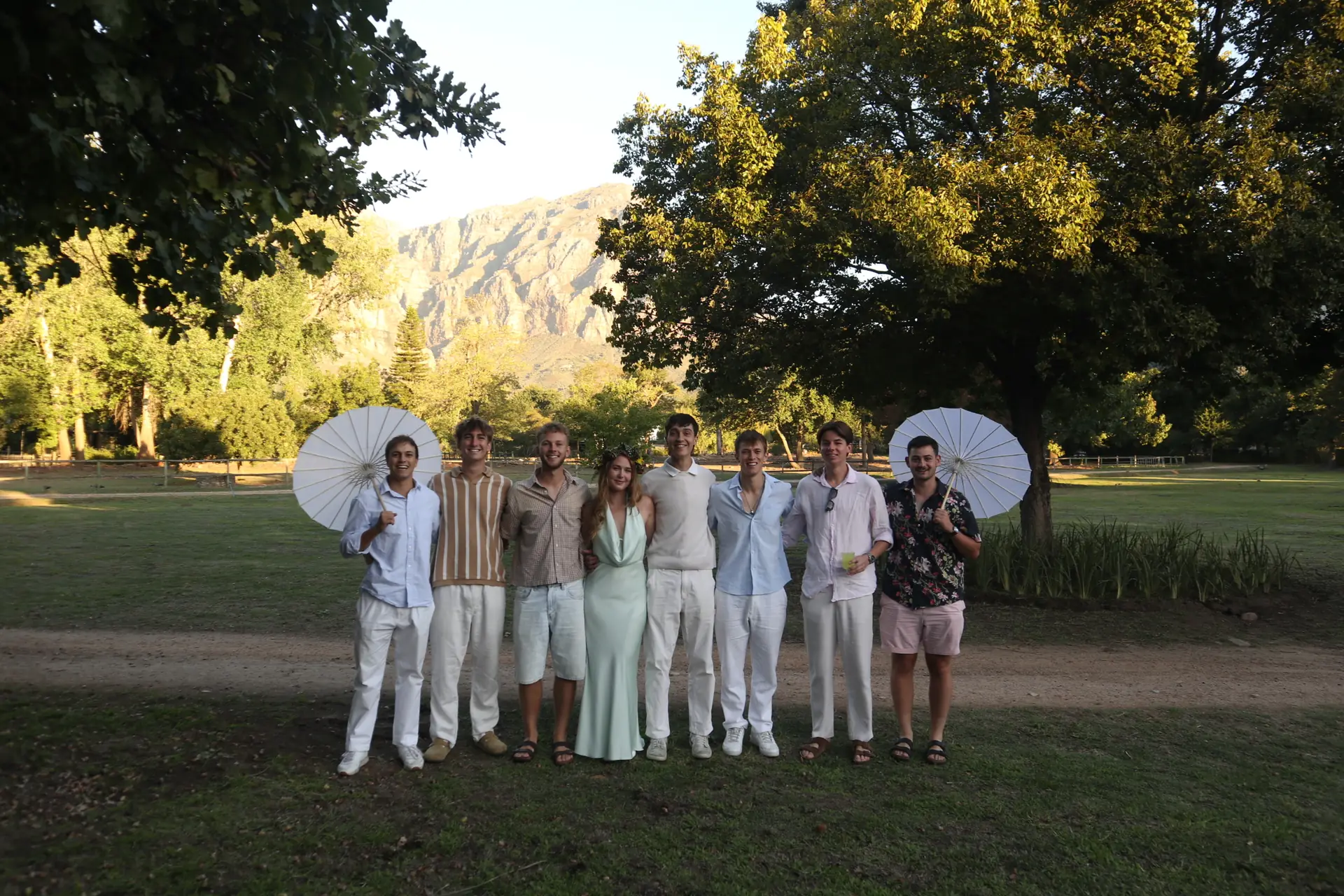 A group of guests posing together on the lawn at Banhoek Stud with the Banhoek mountains behind them