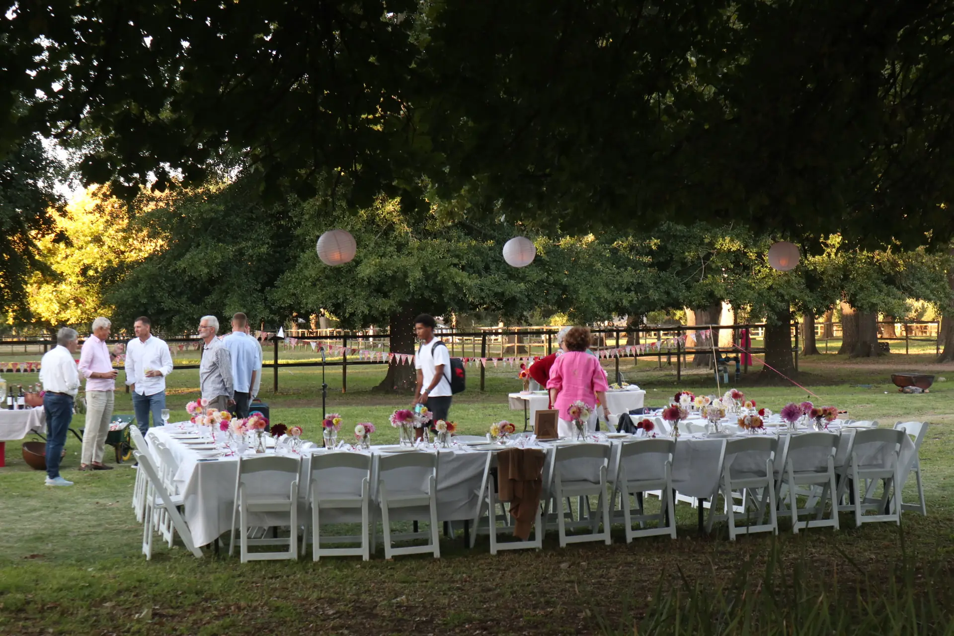 Guests gathered around long white tables for a daytime celebration on the event lawn at Banhoek Stud