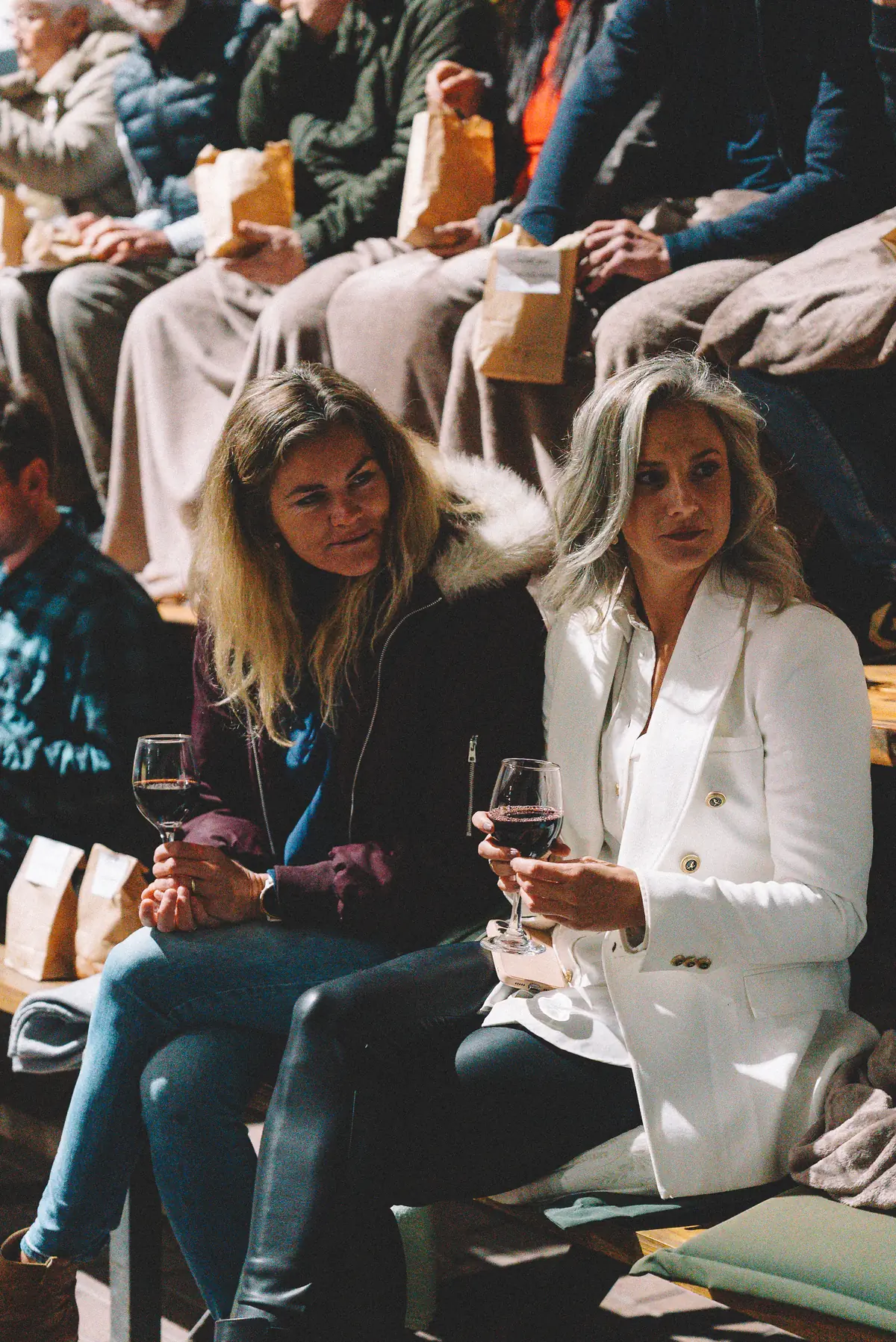 Two guests seated with wine among the audience, blankets over the chairs, at the film premiere