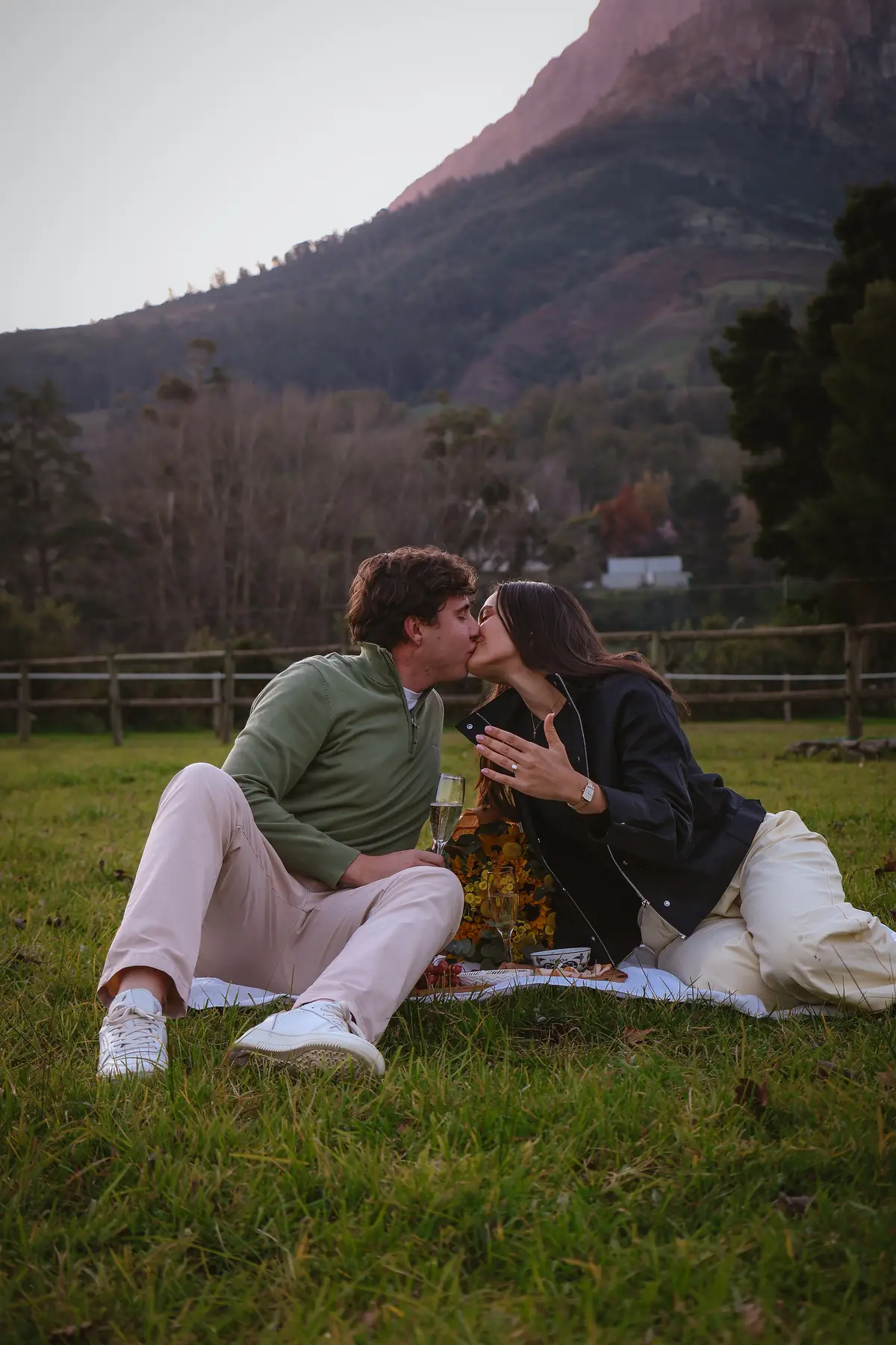 A couple kissing moments after a marriage proposal on the lawn at Banhoek Stud
